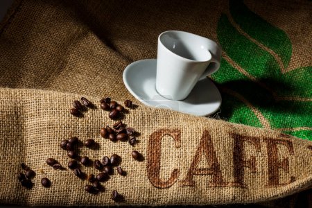 Foto de Taza de café y granos de café sobre fondo de arpillera - Imagen libre de derechos