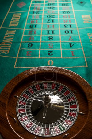 Foto de Ruleta en legno isolata sopra un tavolo da gioco verde con fiches colorate - Imagen libre de derechos