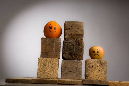 Téléchargez les photos : Orange et pomme avec des visages drôles et des cubes en bois sur fond gris - en image libre de droit