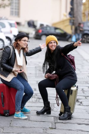 Foto de Pareja de turistas mujeres con maletas en la vieja calle de la ciudad europea - Imagen libre de derechos