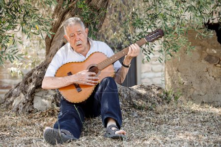 Foto de Hombre mayor tocando la guitarra en el jardín - Imagen libre de derechos
