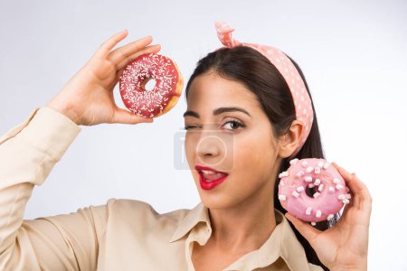 Photo for Beautiful girl with white with black hair and light shirt, plays and has fun with 2 colored donuts, isolated on white background - Royalty Free Image