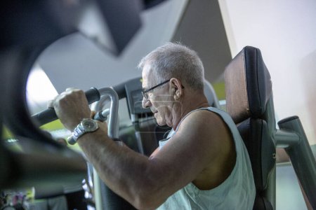 Foto de Hombre mayor hace ejercicios en el gimnasio - Imagen libre de derechos