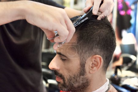 Téléchargez les photos : Un coiffeur qui coupe les cheveux d'un homme - en image libre de droit