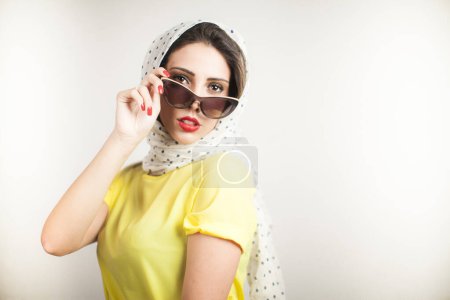 Foto de Chica rubia con la cabeza bufanda y camisa amarilla vestido estilo de los años 50 está aislado sobre fondo gris - Imagen libre de derechos
