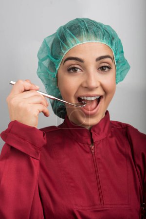 Foto de Dentista con gorra verde en la cabeza y la intención de realizar una operación en un paciente, aislado sobre un fondo claro - Imagen libre de derechos