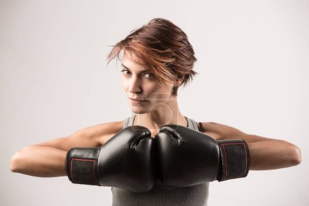 Téléchargez les photos : Heureux boxer femme avec gants de boxe isolé sur fond gris clair - en image libre de droit