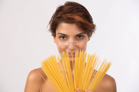 Photo for Beautiful girl plays showing spaghetti by fanning them, isolated on dark background - Royalty Free Image