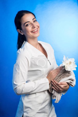 Téléchargez les photos : Brunette fille avec recueilli cheveux apporte serviette, isolé sur fond bleu - en image libre de droit