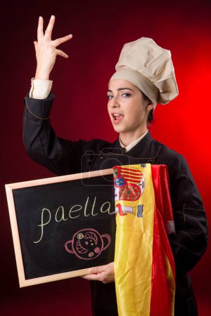 Foto de Cocinero español con bandera y pizarra con paella escrita en ella - Imagen libre de derechos