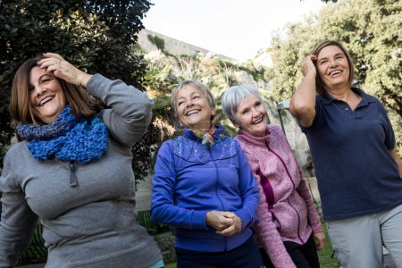 Gruppe fröhlicher Senioren in Sportkleidung, die im Stadtpark Sport treiben