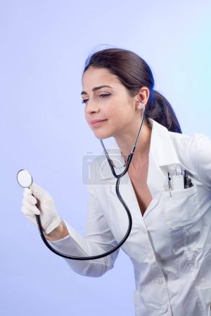 Foto de Médico con una bata blanca y estetoscopio sobre un fondo claro - Imagen libre de derechos