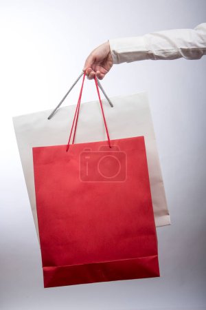 Téléchargez les photos : Femme main tenant des sacs à provisions sur fond gris - en image libre de droit
