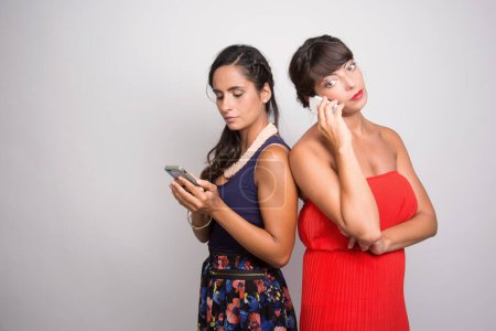 Photo for 2 girls ignore each other because of their smartphone - Royalty Free Image