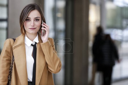 Photo for Blonde female manager with bob hair, white shirt, black tie and beige coat - Royalty Free Image