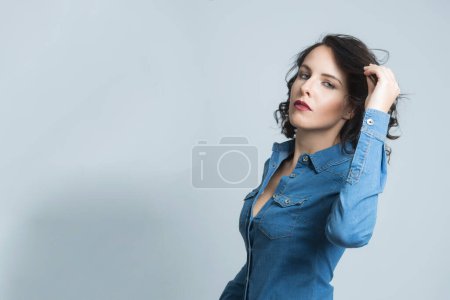 Photo for White model with black hair dressed in a denim shirt, isolated on dark background - Royalty Free Image
