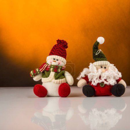 Foto de Santa Claus y muñeco de nieve en la superficie reflectante - Fondo de decoración de Navidad y color mostaza - Imagen libre de derechos