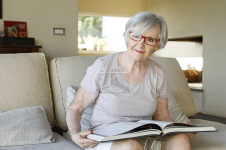Téléchargez les photos : Portrait de heureuse femme âgée assise à la maison - en image libre de droit