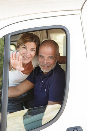 Photo for Couple of gentlemen greets happy from the window of their camper car - Royalty Free Image