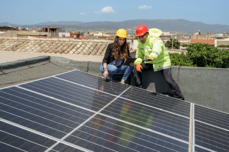Foto de Ingeniero con un trabajador comprueba la instalación de paneles fotovoltaicos en el techo de un edificio - Imagen libre de derechos