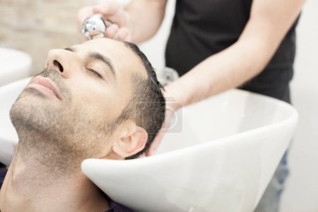 Téléchargez les photos : Un homme se masse le cuir chevelu pendant un shampooing dans un salon de coiffure - en image libre de droit
