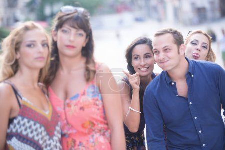 Photo for Group of friends in the background joking around with two girlfriends in the foreground - Royalty Free Image