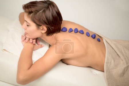 Photo for Woman with bob hair relaxes on the bed of a spa lying on her stomach shot from above with her back in the foreground - Royalty Free Image