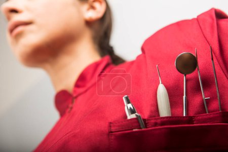 Foto de Detalle de las herramientas de trabajo de un dentista en el bolsillo de su abrigo rojo. - Imagen libre de derechos