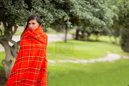Téléchargez les photos : Portrait de belle jeune femme couverte de plaid rouge sur la nature - en image libre de droit
