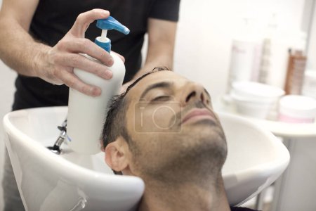 Foto de Un hombre se está masajeando el cuero cabelludo durante un champú en una peluquería - Imagen libre de derechos