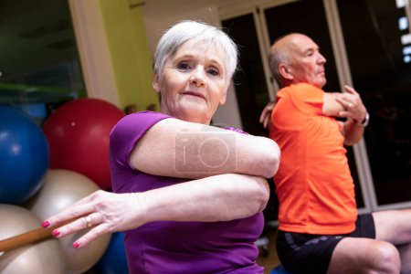 Foto de Pareja de ancianos haciendo ejercicio con pesas en el gimnasio - Imagen libre de derechos