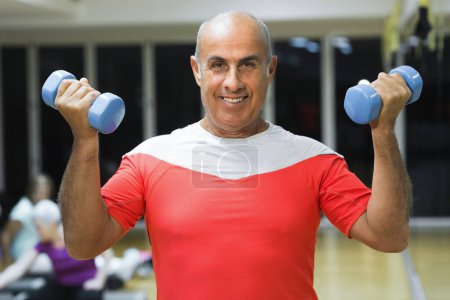 Téléchargez les photos : Homme mature faisant des exercices dans la salle de gym - en image libre de droit