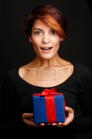 Téléchargez les photos : Belle fille avec chemise noire et heureuse d'avoir un cadeau à jeter dans ses mains, isolée sur fond noir - en image libre de droit