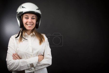 Foto de Chica rubia con casco de moto y camisa blanca aislada sobre fondo negro - Imagen libre de derechos
