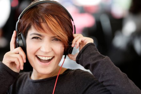 Foto de Hermosa chica morena escuchando música con auriculares en sus oídos - Imagen libre de derechos
