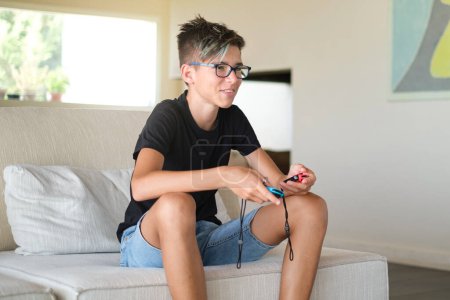 Foto de Adolescente niño juega juego electrónico y disfruta sentado en el suelo en la sala de estar - Imagen libre de derechos