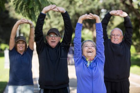 Gruppe fröhlicher Senioren in Sportkleidung, die im Stadtpark Sport treiben