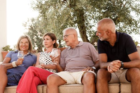 Foto de Personas mayores felices bebiendo vino en la terraza - Imagen libre de derechos