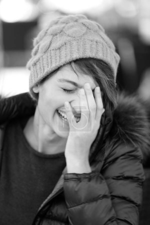 Téléchargez les photos : Portrait de belle fille souriante avec chapeau et manteau, noir et blanc - en image libre de droit