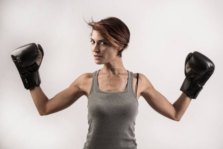Photo for Beautiful girl with bob hair and boxing gloves holds gurdia high, isolated on white background - Royalty Free Image