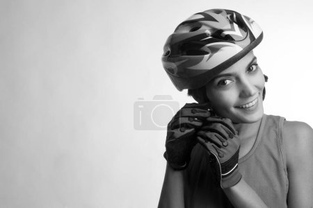 Photo for Smiling woman cyclist fastens the technical helmet, isolated on light background, black and white - Royalty Free Image