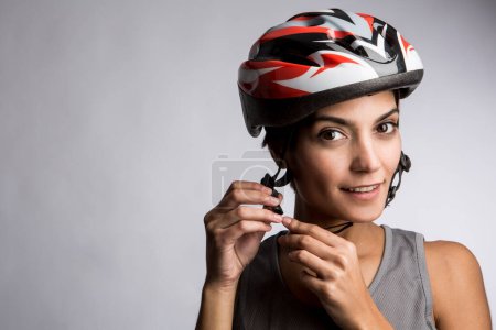 Téléchargez les photos : Femme souriante cycliste attache le casque technique, isolé sur fond clair - en image libre de droit