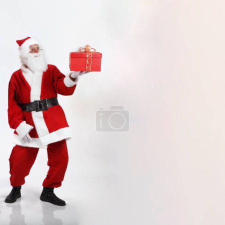 Photo for Santa Claus hands out a red colored parcel, isolated on white background - Royalty Free Image