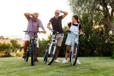 Photo for Three people of different generations enjoy cycling in a green meadow - Royalty Free Image