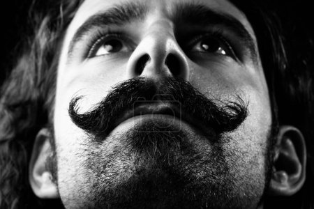 Photo for Man with handlebar mustache and long hair looks serious - Royalty Free Image