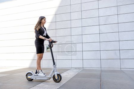 Téléchargez les photos : Gestionnaire féminine avec son scooter dans un environnement urbain moderne - en image libre de droit