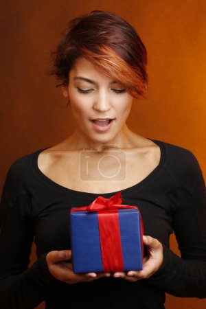 Photo for Beautiful girl with black shirt and happy to have a present to be discarded in her hands, isolated on red  background - Royalty Free Image