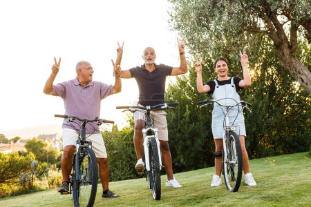 Téléchargez les photos : Trois personnes de différentes générations aiment faire du vélo dans un pré verdoyant - en image libre de droit