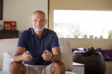 Foto de Hombre de 50 años juega un juego electrónico en su sala de estar - Imagen libre de derechos