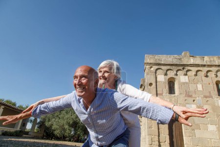 Photo for Happy elderly couple embrace each other smiling, he takes a pony on her - Royalty Free Image